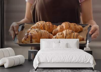 Young woman holding baking tray with fresh croissants indoors Wall mural