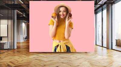 Young woman in hat with tasty muffins on pink background Wall mural