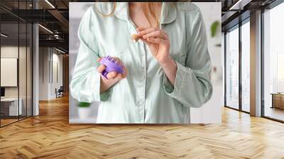 Young woman in pajamas with hair scalp massager and serum at home, closeup Wall mural