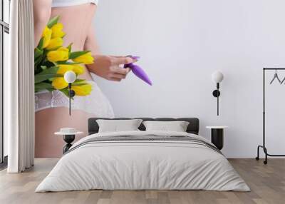 Young woman in panties, with anal plug from sex shop and tulips on light background with space for text Wall mural