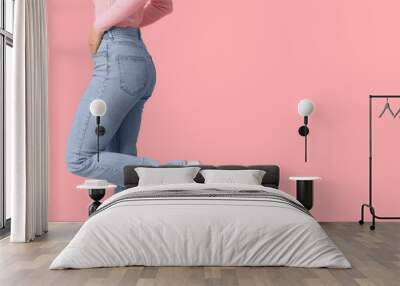 Young woman in stylish jeans on pink background Wall mural