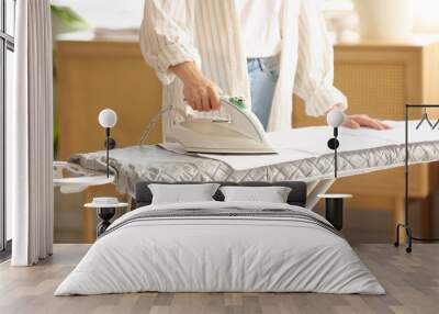 Young woman ironing towel on board in laundry room, closeup Wall mural