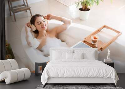 Young woman listening to music while taking bath at home Wall mural