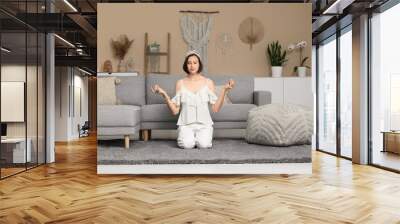 Young woman meditating while sitting on floor at home Wall mural