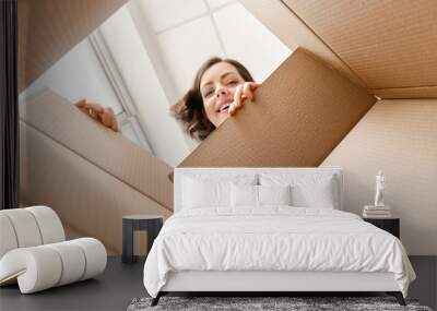 Young woman opening parcel at home, view from inside of box Wall mural