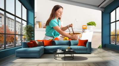 Young woman preparing vegetable salad in kitchen Wall mural