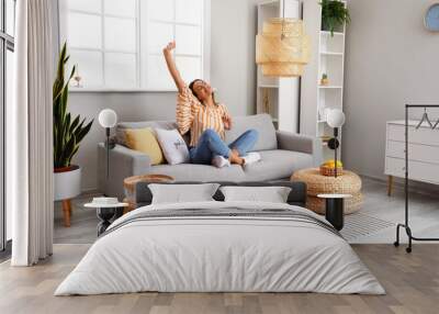 Young woman relaxing on comfortable sofa in room Wall mural