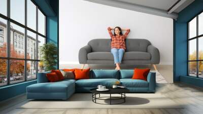 Young woman relaxing on sofa at home Wall mural