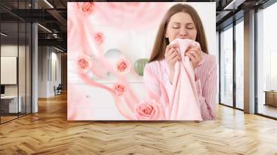 Young woman smelling clean laundry at home Wall mural