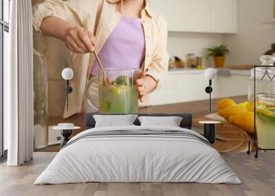 Young woman stirring lemonade in kitchen, closeup Wall mural