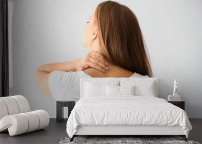 Young woman suffering from neck pain on light background Wall mural