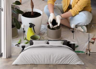 Young woman taking care of green plant at home Wall mural