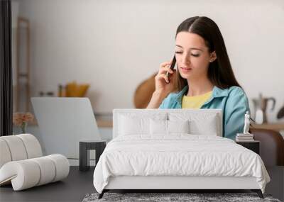 Young woman using laptop and mobile phone at home Wall mural