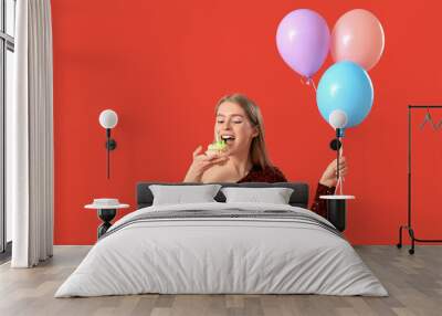 Young woman with birthday tartlet and balloons on red background Wall mural