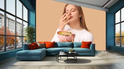 Young woman with bowl of healthy oatmeal on beige background Wall mural