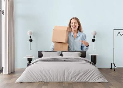 Young woman with cardboard boxes on light background Wall mural