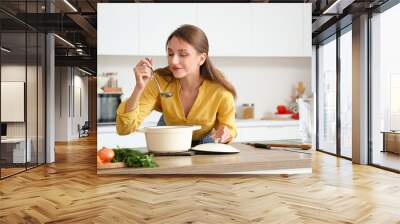 Young woman with chicken soup in kitchen Wall mural