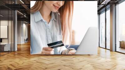 Young woman with credit card shopping online at home Wall mural