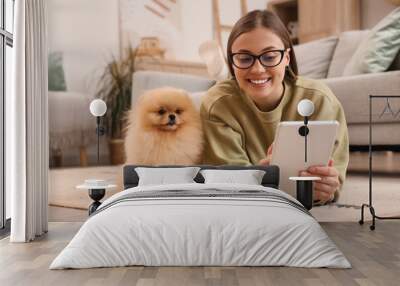 Young woman with cute Pomeranian dog using tablet computer on floor at home Wall mural