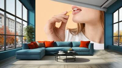 Young woman with healthy fish oil pill on color background, closeup Wall mural