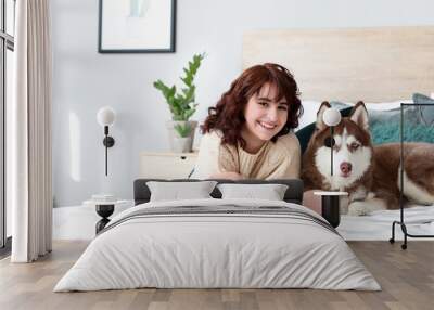 Young woman with her cute dog lying on bed at home Wall mural