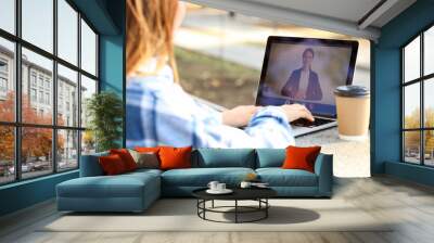 Young woman with laptop video chatting in park, closeup Wall mural