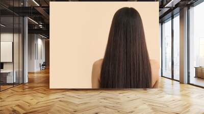 Young woman with long brown straight hair on beige background, back view Wall mural