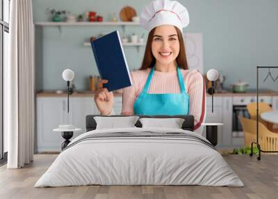 Young woman with recipe book in kitchen Wall mural