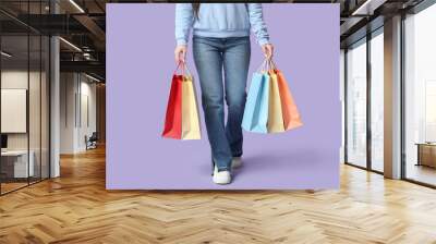 Young woman with shopping bags on lilac background Wall mural