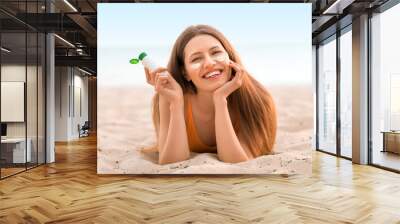 Young woman with sunscreen cream on sea beach Wall mural