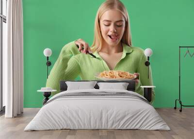 Young woman with tasty pasta on green background Wall mural