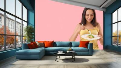 Young woman with tasty pasta on pink background Wall mural