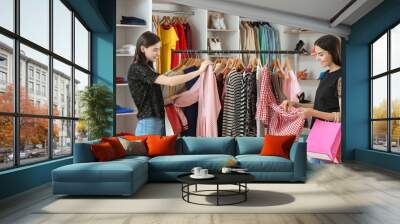 Young women choosing clothes in modern store Wall mural