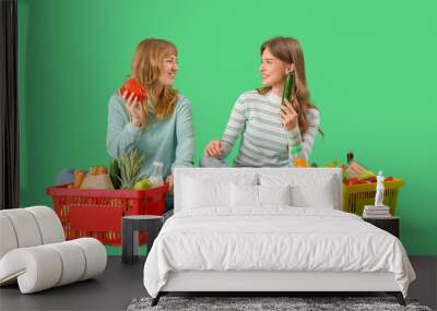 Young women with full shopping baskets on green background Wall mural