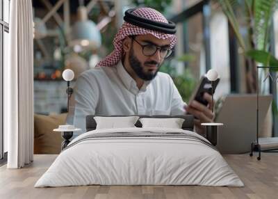 Arab businessman using smartphone and laptop in a cafe Wall mural