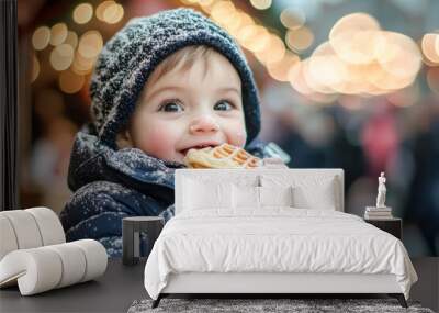 Adorable Child with a Waffle at a Festive Christmas Event. A happy boy with brown hair and light skin stands in the warmth of the holiday lights while eating a waffle on a cold winter's day.
 Wall mural