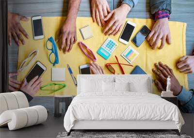 hands on table with cellphones and stationary. overhead shot of young startup team work on a project Wall mural