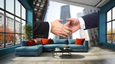 Handshake of two businessmen on the background of office building windows, partnership concept, close up Wall mural