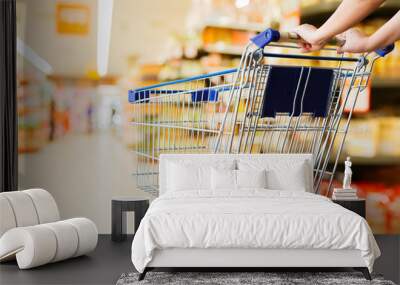 woman pushing shopping cart in supermarket Wall mural