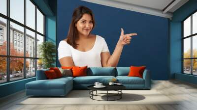 Young woman point finger in copy space Wall mural