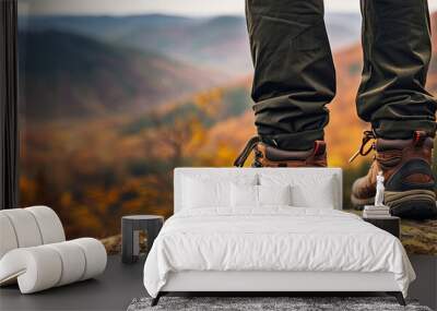 Close-up of a man wearing trekking shoes standing on the cliff with beautiful autumn mountains panorama, Generative AI Wall mural