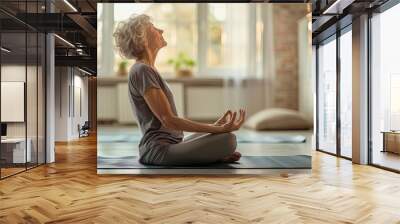 Senior woman meditating on the mat at home Wall mural