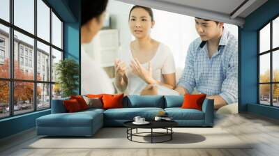 Young couple talking to doctor during counseling session regarding their relationship Wall mural