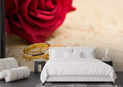 wedding rings and artificial rose on brown background Wall mural