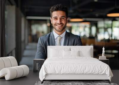 Portrait of a smiling young businessman standing with arms crossed in office Wall mural