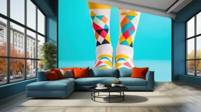 Colorful geometric-patterned socks against a vibrant turquoise background showcase fun and stylish fashion. Wall mural