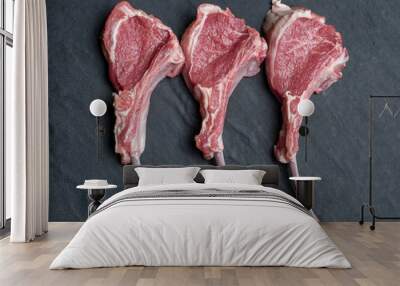 three raw lamb chops on a black slate plate from above Wall mural