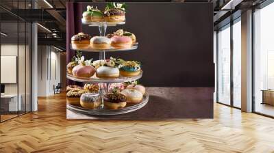 An elegant vertical arrangement of gourmet donuts on a clear acrylic stand, each donut decor. Wall mural