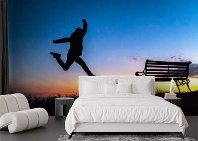 Silhouette of happy boy jumping against beautiful twilight sky over a mountain. Freedom enjoyment concept. Wall mural