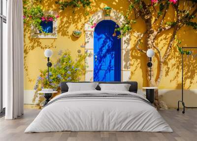 Blue door of a yellow Greek house decorated with flowers, Assos town, Kefalonia island, Greece Wall mural